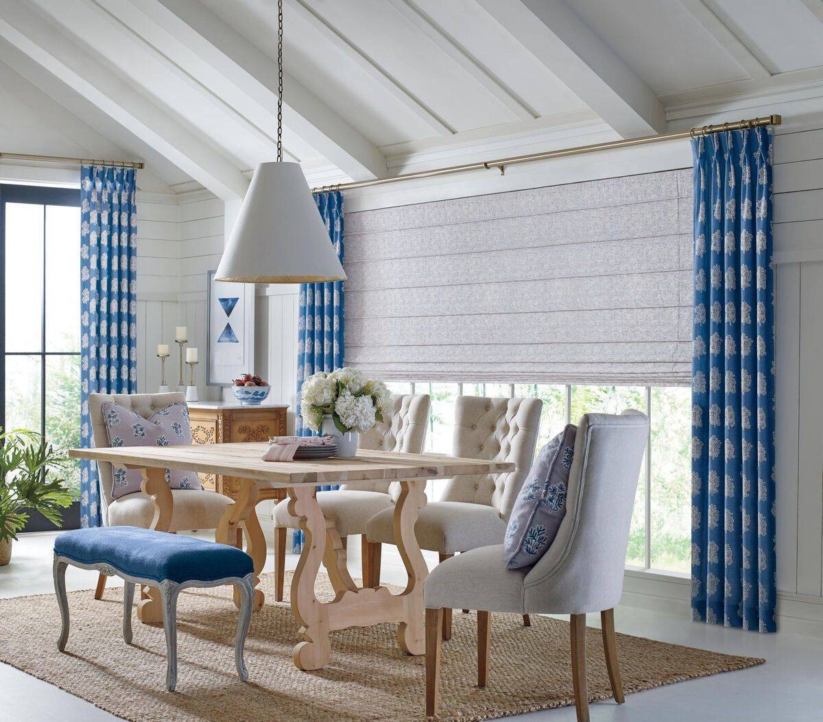 Dining room with dark blue Hunter Douglas drapery and shades covering a long window